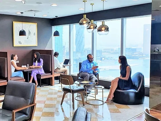 A stylish and welcoming Servcorp business lounge with panoramic city and waterfront views, where professionals are seen networking and relaxing